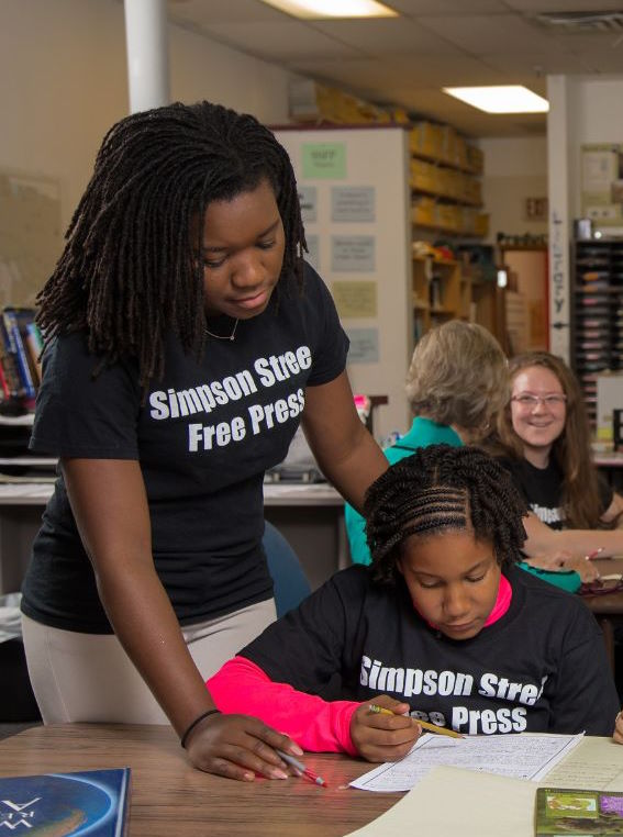 Black woman helping Black female teenager work on Simpson Street Free Press newspaper